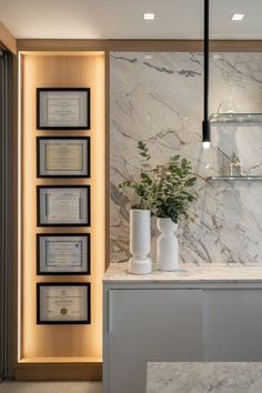 a white marble counter top with vases and books on it in front of a wall