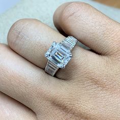 a woman's hand with a diamond ring on top of her finger and an engagement band