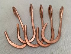 several copper colored metal hooks on a white surface