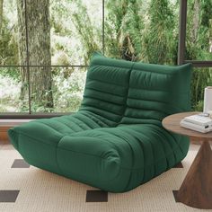 a green chair sitting on top of a rug next to a table