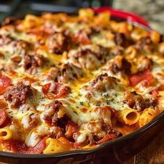 a casserole dish with meat and cheese on it sitting on a wooden table