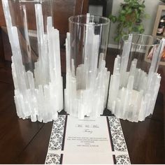 a table topped with tall clear vases filled with water next to a white paper