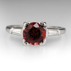 This lovely vintage ring is centered with one (1) round brilliant cut natural rhodolite garnet set into a four-prong setting. The shoulders of the ring are each accented with one (1) channel set, tapered baguette cut diamond. The ring measures 7.6mm at the top, rises 8.1mm above the finger, tapering to 1.2mm wide and 1.1mm thick at the base of the shank. It is currently a size 6.25. Elegant Garnet Ring With Prong Setting, Elegant Platinum Ruby Ring With Round Cut, Elegant Garnet Birthstone Ring With Center Stone, Elegant Ruby Ring With Diamond And Round Stone, Elegant Formal Ruby Ring With Round Stone, Elegant Lab-created Ruby Diamond Ring With Accent Stones, Elegant Burgundy Garnet Rings, Classic Diamond Ring With Lab-created Ruby Accent Stones, Classic Diamond Ring With Round Gemstone