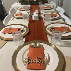 the table is set with orange napkins and place settings for an elegant thanksgiving dinner