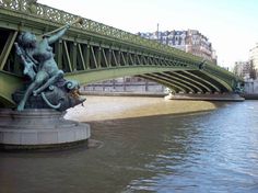 a statue on the side of a bridge next to water