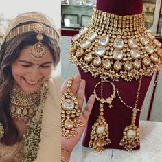 a woman is showing off her gold jewelry set and smiling at the camera while sitting in front of a mannequin