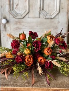 a bouquet of flowers sitting on top of a wooden table in front of a door