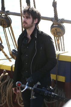 a man standing next to a bike on top of a boat with ropes and bells