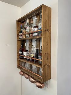 a wooden shelf filled with lots of bottles and glasses on top of a white wall