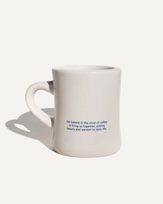 a white coffee cup with blue writing on the outside and inside, against a white background