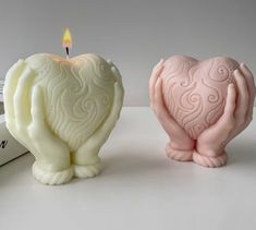 two small candles sitting next to each other on top of a white table with books