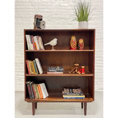 a book shelf with books and other items on it in front of a brick wall