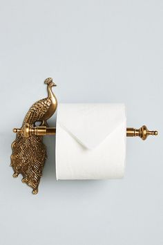 a toilet paper holder with a gold peacock on it and a white envelope in the middle