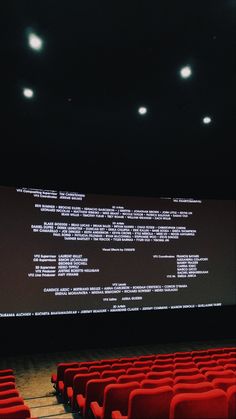 an empty theater with rows of red seats in front of a projector screen that is projected on the wall