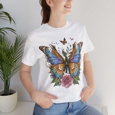 Butterfly Flowers T-Shirt, Nature Lover Shirt, Botanical Tshirt This classic unisex jersey short sleeve tee fits like a well-loved favorite. Soft cotton and quality print make users fall in love with it over and over again. These t-shirts have-ribbed knit collars to bolster shaping. The shoulders are tapered for a better fit over time. Dual side seams hold the garment's shape for longer.  - Made with 100% Airlume combed and ring-spun cotton, a lightweight fabric (4.2 oz/yd² (142 g/m that is easy to layer, breathable. Perfect for active and leisure wear.  - The retail fit that is perfect for casual and semi-formal settings. The crew neckline adds a classic, neat style that's perfect for accessorizing. - Bella+Canvas manufactures all its products in the US and internationally in humane, no-s Cotton Tops With Butterfly Print And Short Sleeves, Short Sleeve Cotton Tops With Butterfly Print, Short Sleeve Graphic Tee With Butterfly Print, Butterfly Print Short Sleeve Graphic Tee, Short Sleeve Butterfly Print Graphic Tee, Relaxed Fit Butterfly Print Graphic Tee, Botanical Tshirt, White Butterfly T-shirt For Spring, Cute Short Sleeve T-shirt With Butterfly Print