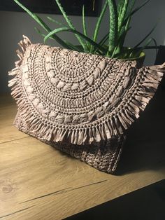 a small purse sitting on top of a wooden table next to a potted plant