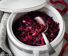 a white pot filled with red cabbage next to a plate on a cloth covered table