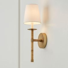 a wall light that is on the side of a white wall with a lamp shade