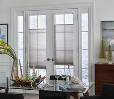 a dining room table with chairs and vases on top of it next to two windows