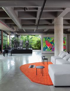 a living room with white couches and orange rugs on the floor in front of large windows