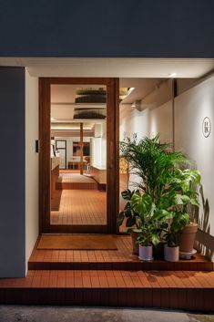 an open door leading to a hallway with potted plants