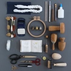 various crafting supplies are laid out on a gray surface with scissors, thread, and other items