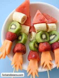 fruit skewers are arranged in the shape of claws on a white plate with watermelon, kiwi and strawberries