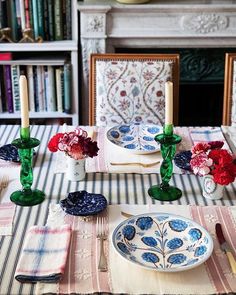 the table is set with plates, candles and flowers in vases on top of them