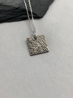 This minimalist tiny modern necklace has been entirely handmade using .999 fine silver. It has been cut out from fine silver precious metal clay, textured, fired and oxidized. The pendant hangs from a sterling silver diamond cut cable chain. This fine silver pendant features a simple modern embossed textured pattern on one side of the pendant and is reversible to a embossed pattern on the reverse side. Pendant size: approximately 1/2 x 1/2 inches Chain length: adjustable at 16 and 18 inches can Layered Necklaces Boho, Silver Necklace Simple, Moon Necklace Silver, Modern Necklace, Silver Bar Necklace, Square Necklace, Layered Necklaces Silver, Precious Metal Clay, Necklace Layering