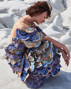 a woman sitting on the ground wearing a dress made out of different colored materials