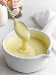 a spoon full of mayonnaise being drizzled into a white bowl