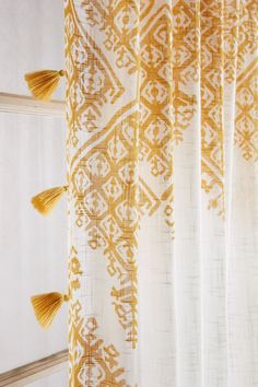 yellow and white curtains with tassels hanging from them