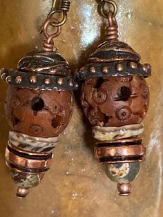 Listen closely and you may hear these earrings beaconing to those who resonate with and earthy, rustic style. The primary focal bead is an intricately carved wooden bead topped with two beautifully made Anna Bronze caps. Below the wood bead is shell "cap", copper spacer bead, and etched agate bead and a tiny copper bead.  The main body of the earring is about 1", with the ear wire the drop length is 1&3/4". The widest point at the dotted bead cap is 1/2".  Feel free to message me if you have any questions and thanks for your interest! Handmade Bohemian Brown Earrings, Earthy Handmade Beaded Dangle Earrings, Handmade Brown Bohemian Earrings, Handmade Earthy Earrings For Festival, Unique Brown Beaded Earrings As Gift, Unique Brown Beaded Earrings For Gift, Brown Bohemian Earrings With Round Beads, Artisan Copper Beaded Earrings As Gift, Artisan Rust-colored Earrings As Gift