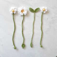 three crocheted flowers sitting on top of a white countertop next to each other