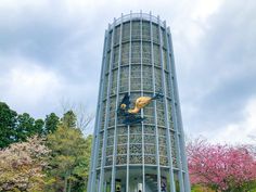 a tall building with a statue on the side of it's face in front of some trees