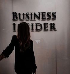 a woman standing in front of a sign that says business insider on the side of a building