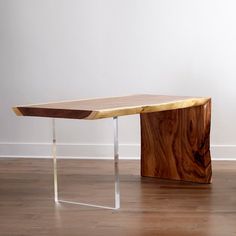 a wooden table sitting on top of a hard wood floor next to a white wall