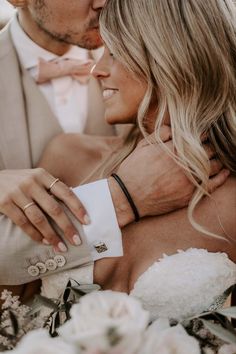 a bride and groom embracing each other in their wedding day attire with flowers on the bouquet