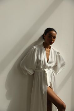 Our long bridal silk robe with wide long sleeves. It could be made of satin or pure mulberry silk. The robe is both casual and elegant, you may wear it on the hen party or spontaneously around your home on a daily basis. It is also an amazing outfit for your vocation, to wear it on the beautiful beach or by the pool as a cover up. -Our model wears size XS, her measurements are 82/61/87 cm and she is 172 cm tall. -Attached with belt. -Arrives beautifully packaged in tissue paper with ribbon -Leng Long Silk Robe For Wedding Night, Satin V-neck Robe For Daywear, Silk Wrap Robe For Wedding Night, Elegant Open Front Kimono For Wedding, White V-neck Robe For Sleep, Elegant White Open Front Robe, Elegant Wedding Night Sleepwear With Kimono Sleeves, Elegant Sleepwear With Kimono Sleeves For Wedding Night, Elegant Silk Summer Robe