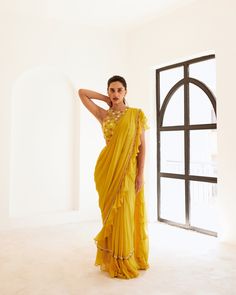 Yellow net blouse paired up with yellow predraped frill saree having hand embroidered border in between.Yellow predraped frill saree No. of pieces in a set: 3 Color: Yellow Fabric Composition: Net, georgette, opada silk Lining Material: Shantoon Closure used: Side zip in both blouse and saree Dress Length : Full Silhouette: Saree Neck type : Halter round Sleeve Length: Sleeveless Waistline: High waist Prints/ Pattterns : Plain Delivery Time: 20-25 days Ruffled Georgette Saree In Traditional Drape, Ruffled Georgette Saree With Traditional Drape, Yellow Organza Pre-draped Saree For Reception, Festive Silk Chiffon Pre-draped Saree, Yellow Pre-draped Saree For Wedding, Georgette Saree With Draped Pallu, Traditional Ruffled Dupatta For Navratri, Elegant Yellow Pre-draped Saree With Traditional Drape, Anarkali Saree With Ruffles In Traditional Drape