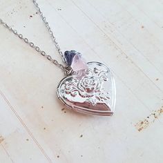 This pretty silver plated locket with palest pink and shimmering grey glass flower beads is suspended from silvr plated chain. Choose your perfect length. It has a beautiful raised rose motif on the front, and is plain on the back. The vintage style locket measures just over 1 1/4 inches (30 mm) across, and opens to reveal space for two photos, or a little secret. The antique silver plated chain has a lobster clasp and extension chain, choose your length from the drop down menu. This locket come Cheap Silver Pendant Locket Necklace, Unique Locket Necklace Silver, Silver Locket Jewelry For Mother's Day, Mother's Day Silver Locket Jewelry, Wedding Necklaces With Flower Charm In Metal, Wedding Necklace With Flower Charm In Metal, Delicate Silver Heart Jewelry, Delicate Heart Shaped Silver Jewelry, Silver Heart Beads Charm Necklace For Wedding