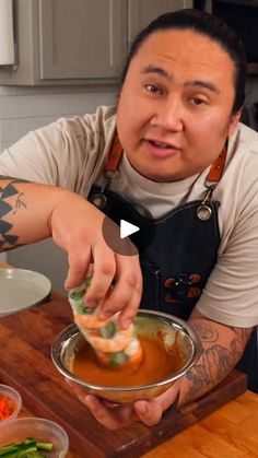 a man in an apron is dipping food into a bowl