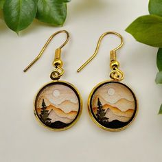 Celebrate your love with the timeless beauty of nature with our exquisite Mountain Landscape Dangle Earrings. Perfect for a 5th wooden anniversary gift for her, these earrings capture the serene essence of a forest sunrise, making them a unique and thoughtful present. Handcrafted with meticulous attention to detail, each pair features a stunning wooden landscape that showcases the majestic mountains and lush forests, bringing a touch of the great outdoors to her everyday style. Crafted from high Nature-inspired Gold Earrings For Anniversary, Nature-inspired Everyday Jewelry With Matching Earrings, Single Round Pendant Earring As A Gift, Nature-inspired Hypoallergenic Gold Jewelry, Hypoallergenic Nature-inspired Gold Jewelry, Nature-inspired Single Earring As Gift, Nature-inspired Yellow Gold Earrings For Gift, Nature-inspired Yellow Gold Jewelry With Matching Earrings, Hypoallergenic Gold Nature-inspired Jewelry