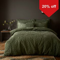 a bed covered in green bedspread and pillows next to a red sign that says 20 % off