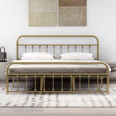 a metal bed frame with white sheets and pillows on top of it in a room