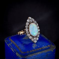 an opal and diamond ring on top of a blue box