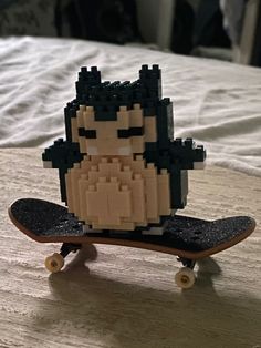 a lego figure sitting on top of a skateboard in the middle of a bed