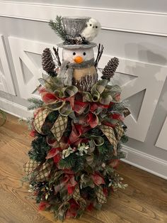 a snowman made out of pine cones and evergreens with a bird perched on top