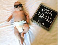 a baby doll laying on top of a bed next to a sign that says three months summer bodyready