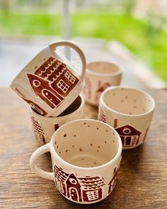 four coffee mugs sitting on top of a wooden table next to eachother